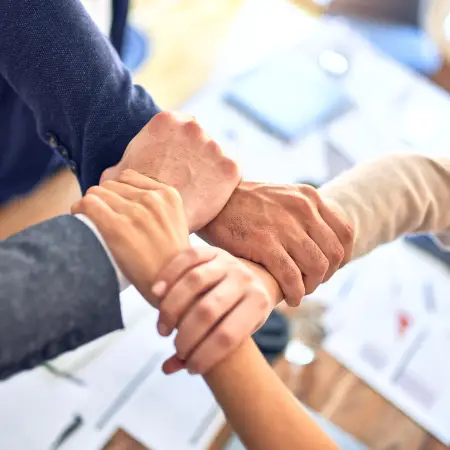 Hands of four people grabbing each other's wrist to make a square.